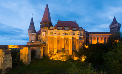 Fototapeta na wymiar Corvin Castle is on the green mountain in night of Romania.