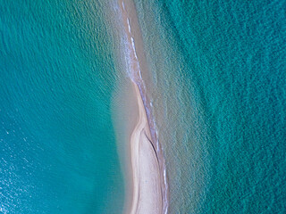 Aerial view of exotic long sand beach with sea on both sides 