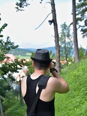 Travel photographer making photo of the nature. Man in a hat.