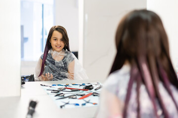 Fototapeta premium little girl dyes her hair purple in a hairdressing salon