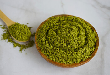 Moringa powder in wooden bowl on marble background .Balanced nutrition concept for clean eating...