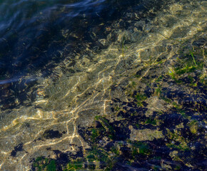 Sea bottom with pebbles through clear water. Natural background.