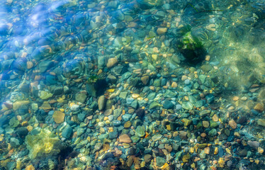 Sea bottom with pebbles through clear water. Natural background.