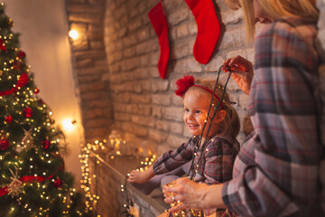 Mother and daughter holding Christmas lights