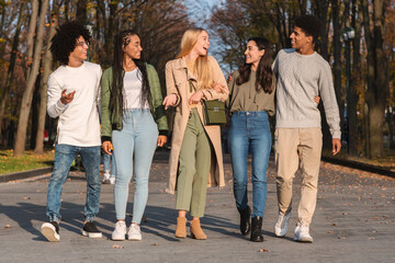 Obraz na płótnie Canvas Full size photo of happy teenagers walking in park