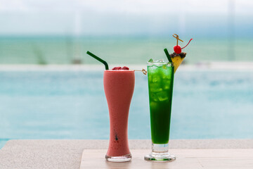 Cocktails served cold at pool bar. Raspberry smoothie and Green cocktail with pineapple slices at pool.