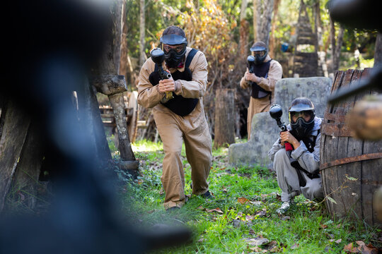 Adult paintball players of opposite teams playing in shootout outdoors