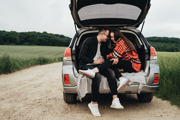 Young Beautiful Couple Sitting in the Car Trunk and Enjoying the Roadtrip
