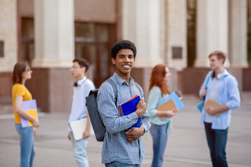 Happy African Student Posing With Books Standing Near University Outdoor