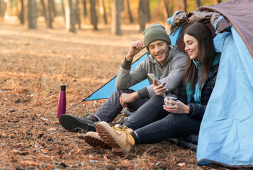 Romantic couple camping outdoors, sitting in tent and talking