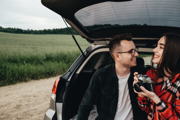 Young Beautiful Couple Sitting in the Car Trunk and Enjoying the Roadtrip