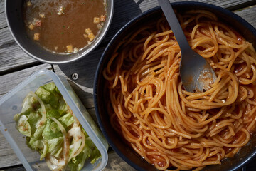 屋外の木のテーブルで食べるパスタ・スープ・サラダ