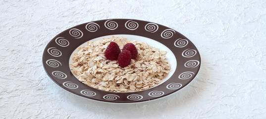 Plate with oatmeal and raspberries on a white background.