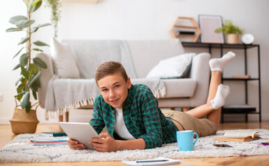 Fototapeta na wymiar Teen boy using digital tablet while doing homework