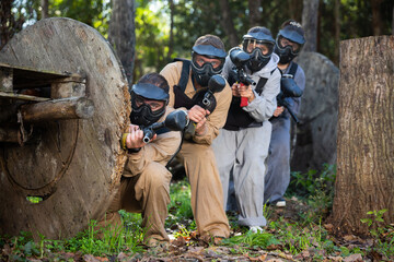 Men and women in protective uniform playing paintball on shooting range