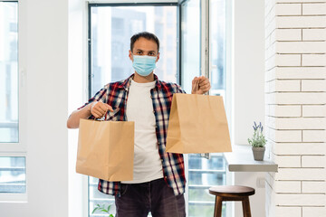 Delivery man holding paper bag with food, food delivery man in protective mask