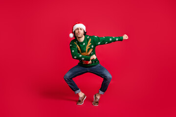 Full length body size view of his he nice attractive childish glad cheerful guy wearing Santa cap dancing having fun newyear festive fooling isolated bright vivid shine vibrant red color background