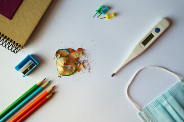 School supplies, a medical mask, and a thermometer - back to school concept in the new normal