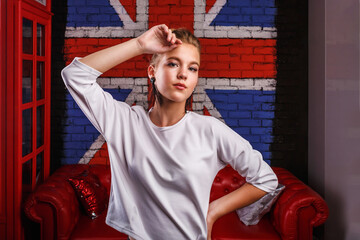 Fashion glamorous portrait of a girl model with white sweater on wall background with a British flag