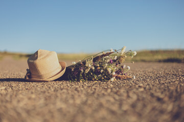 Image of  old suitcase,hat and flowers on the country road.