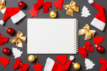 Top view of notebook on black background with New Year toys and decorations. Christmas time concept