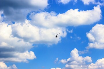 High flying helicopter in the cloudy sky.