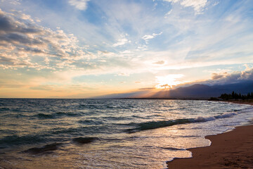 Obraz premium Beautiful sunset by the lake. Bright clouds are reflected in the water. Kyrgyzstan.