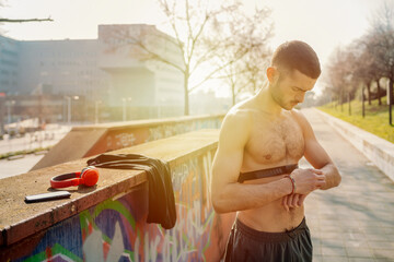 Young man using fitness tracker while standing on street