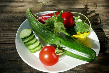 Fresh vegetables in a white plate on a wooden background
