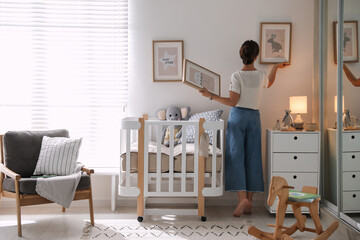 Decorator hanging pictures on wall in baby room. Interior design