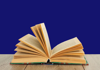 Open book textbook in colorful cover on a blue background. Back to school distance home education.Quarantine concept of stay home.