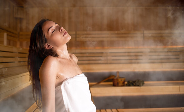 Beautiful woman in white towel relaxing in sauna