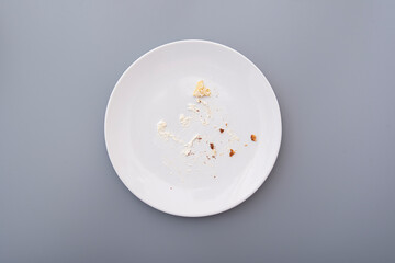 White plate with crumbs and cream after sweet cake, top view