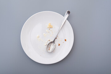 White plate with crumbs and cream after sweet cake, top view