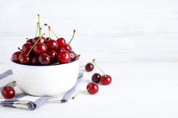 Sweet juicy cherries on white wooden table. Space for text