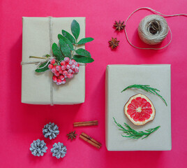 Minimalistic stylish bright Christmas composition of gift boxes in craft paper on a red...