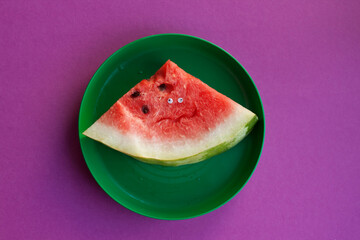 Sliced ​​watermelon with eyes lies on a green plate
