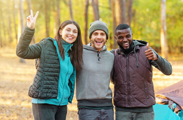 Young cool hikers posing over camp in forest