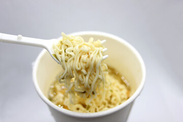 instant noodles, noodle soup in a cup, view from above. Instant noodles are sold in a precooked and dried noodle block, with flavoring powder and/or seasoning oil.