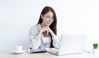 Young Asian woman works on paperwork in her own home online.