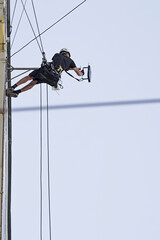 Industrial climbing. A construction worker abseiling and suspending in safety ropes. Washing windows, cleaning walls, maintenance.
