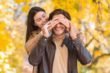Woman closing eyes of her boyfriend, dating in autumn park