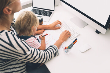 Mother working from home with little child.