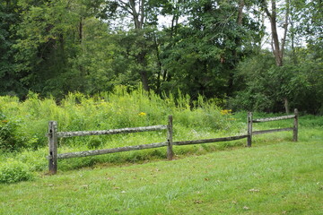 The broken wooden fence on a green meadow.