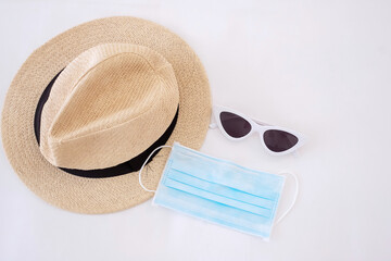 Travel under Covid-19 and new normal concepts. medical face mask, sunglasses and beach hat on white bed, prevent coronavirus or Corona Virus Disease