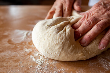 Fresh homemade dough is kneaded by grandmother's hands. Side view.