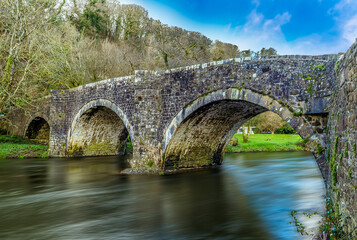 A long exposure view to produce smooth, dreamy water flowing beneath the Llawhaden bridge, an eighteenth-century, grade 2 listed bridge that spans the River Cleddau, Wales