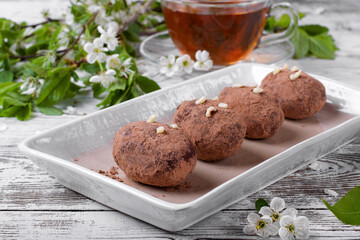 Kartoshka cake on the ceramic platter and a cup of tea. Russian potato-shaped dessert
