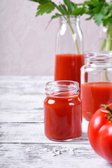 Tomato juice in glass jars on white wooden table. Copy space