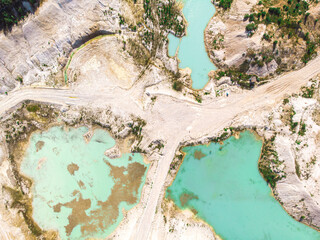 Naklejka premium Drone view on a flooded kaolin quarry with turquoise water and white shore. Aerial survey of a kaolin pit flooded with water.